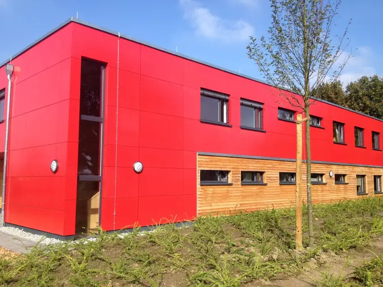 Büro- und Produktionsgebäude mit roter Fassade und Holzverkleidung in Burscheid