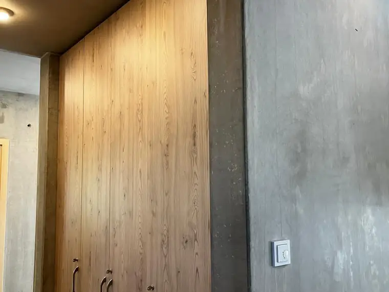 Innenraum mit Einbauschrank in Holz vor einer Sichtbetonwand