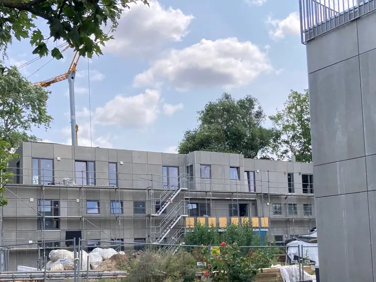 Baustelle der seriellen Sanierung mehrerer Wohnhäuser mit Gerüst und Kran